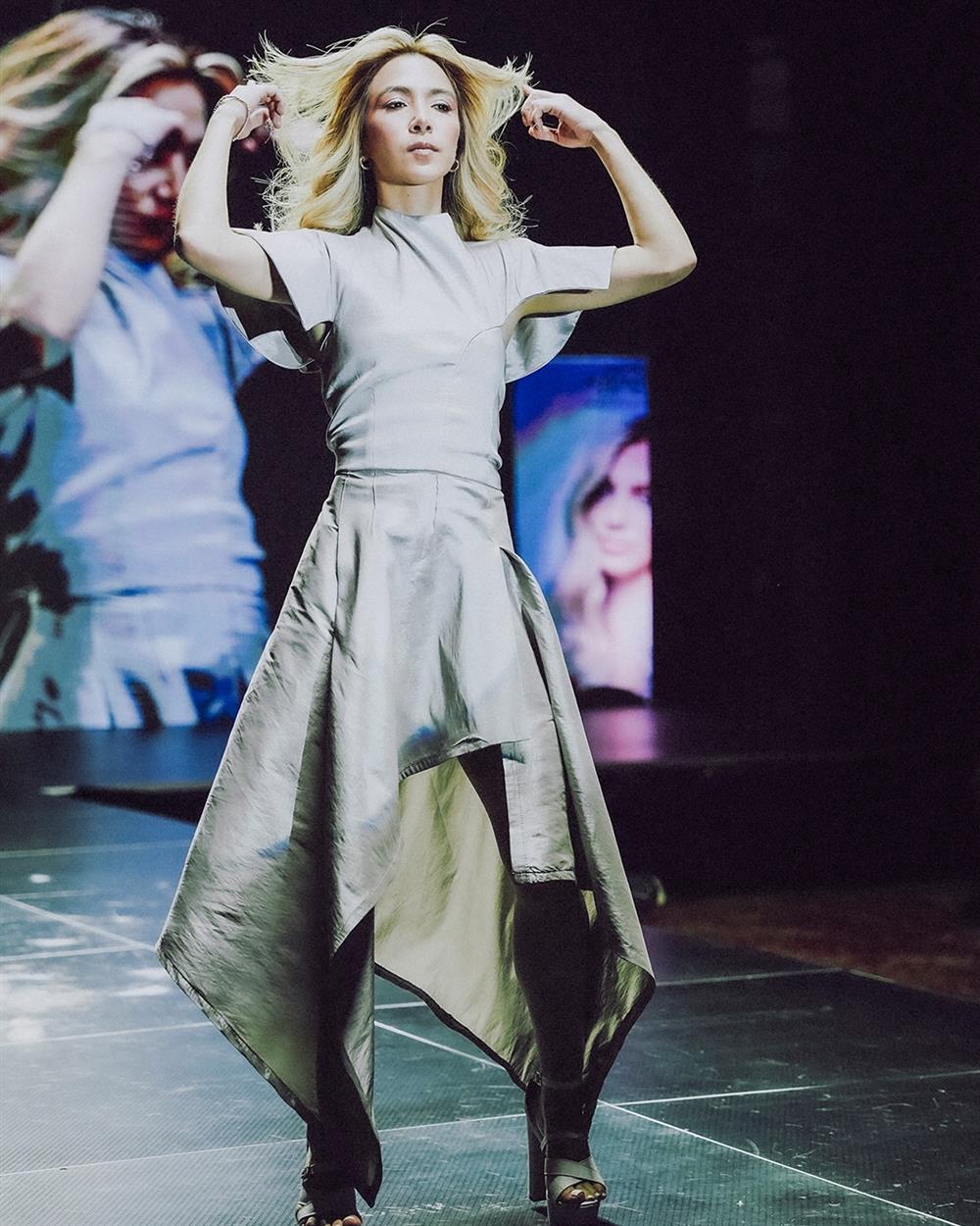 Modelo rubia desfilando con vestido gris asimétrico